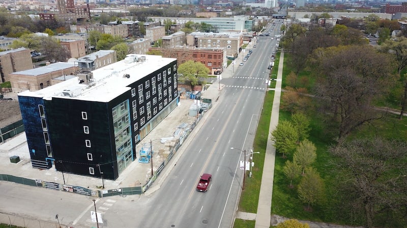 An aerial photo focused on a five-story affordable housing building, under construction when the photo was taken, that opened in 2022 for veterans. Roosevelt Road is in the foreground.